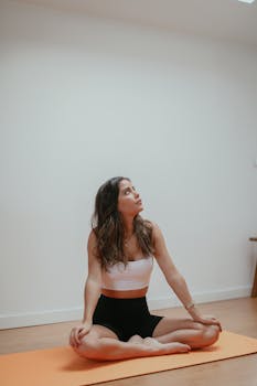 Young woman sitting in a yoga pose indoors, exuding mindfulness and calm.
