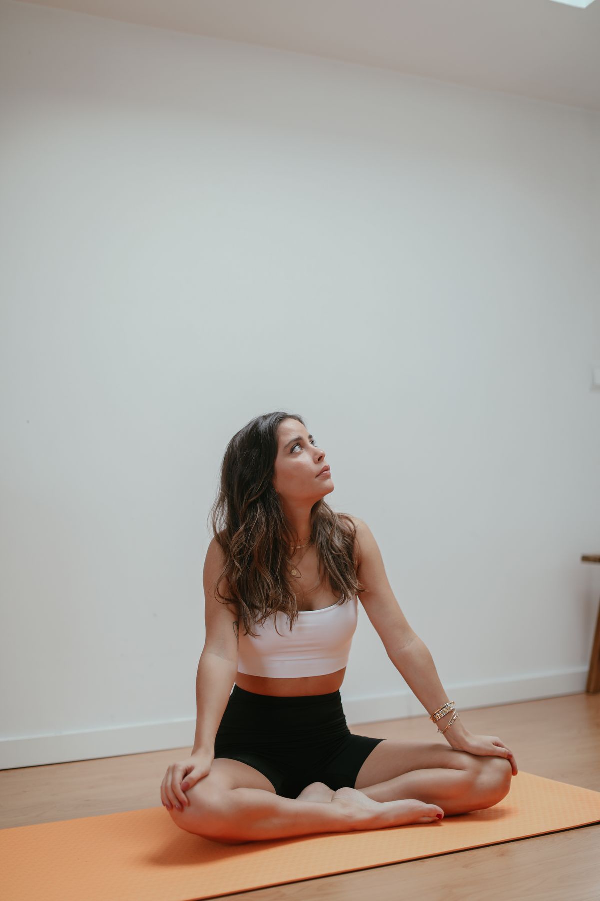 Woman seated on a yoga mat in a mindful, meditative posture, reflecting the Ayurvedic principle of matching practice to individual constitution