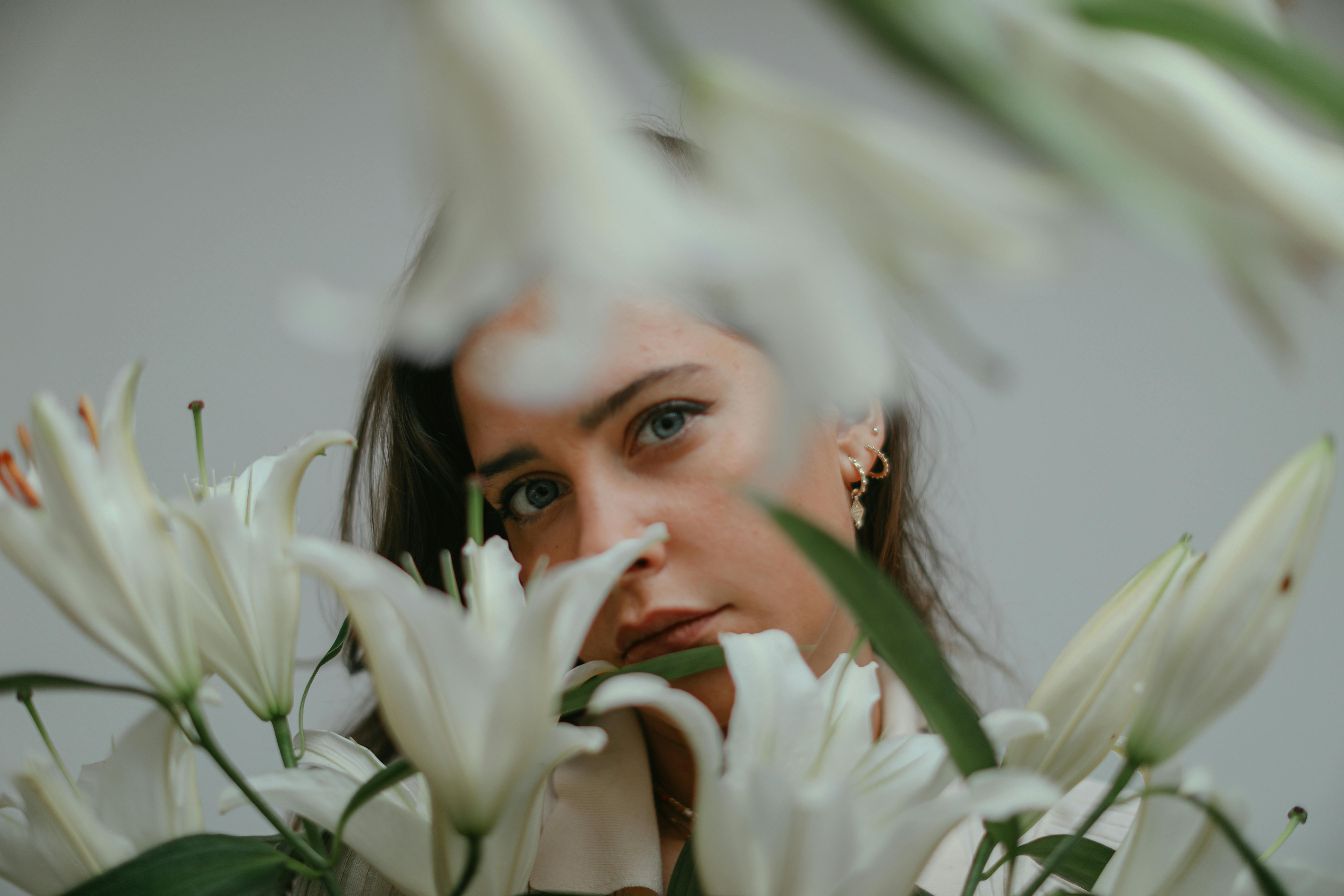 Artistic portrait of a woman surrounded by white lily flowers, capturing serene elegance.