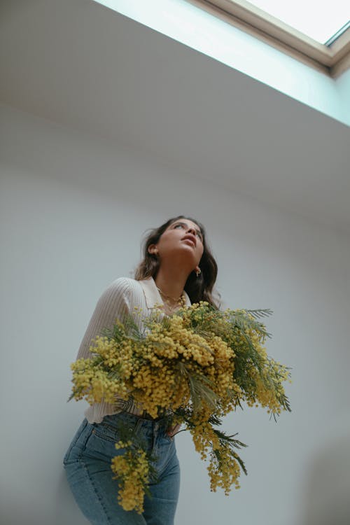 Low Angle Shot of a Beautiful Woman Holding Yellow Flowers