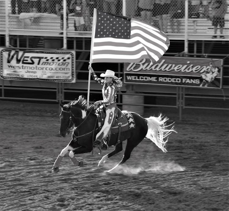 Woman Riding On Horseback And Waving An American Flag