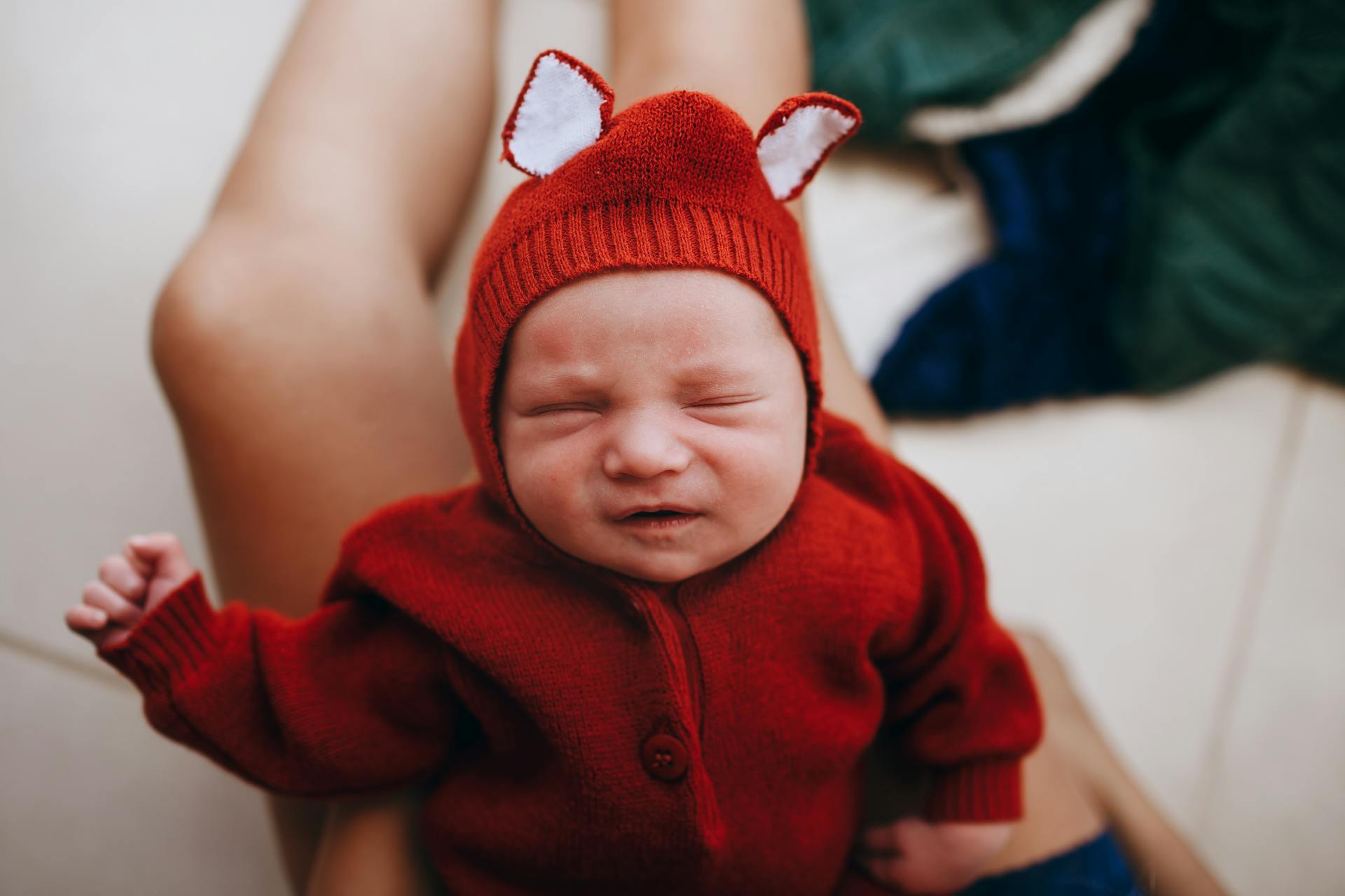 Top view of crop anonymous female with small adorable infant crying on blurred background