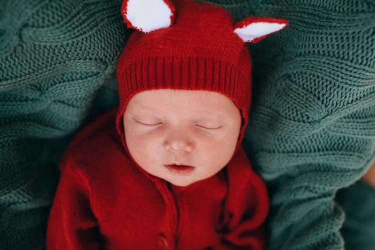 Little Funny Infant In Red Knitted Costume Sleeping