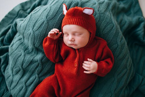 Free Small cute baby with gentle little hands sleeping on blanket Stock Photo