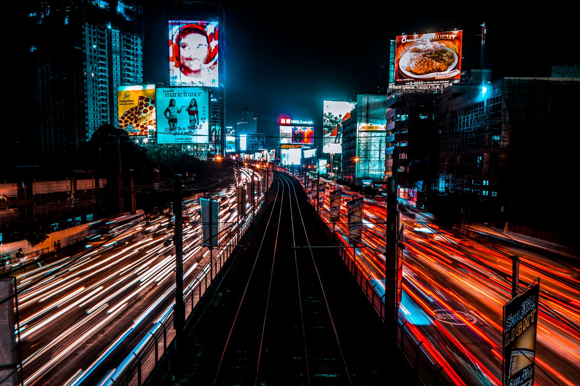 Dynamic cityscape at night showcasing vibrant light trails and illuminated billboards.