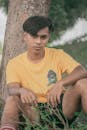 Young Man Sitting and Leaning Against a Tree