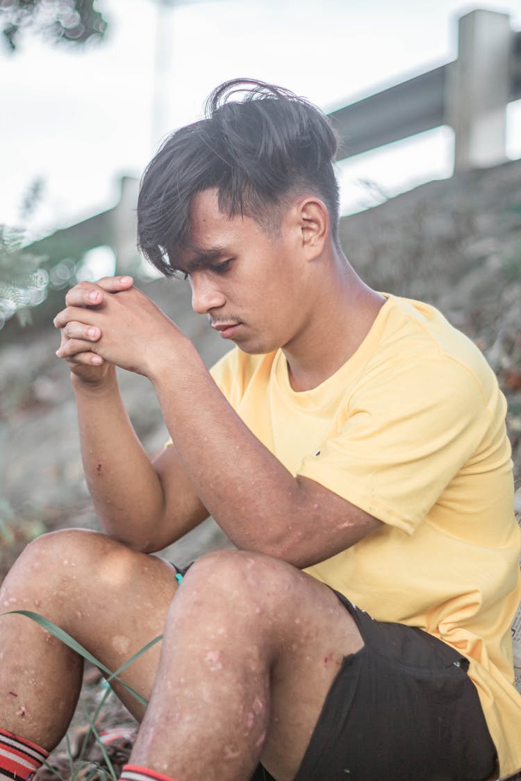 Young Man Sitting On Ground Thinking