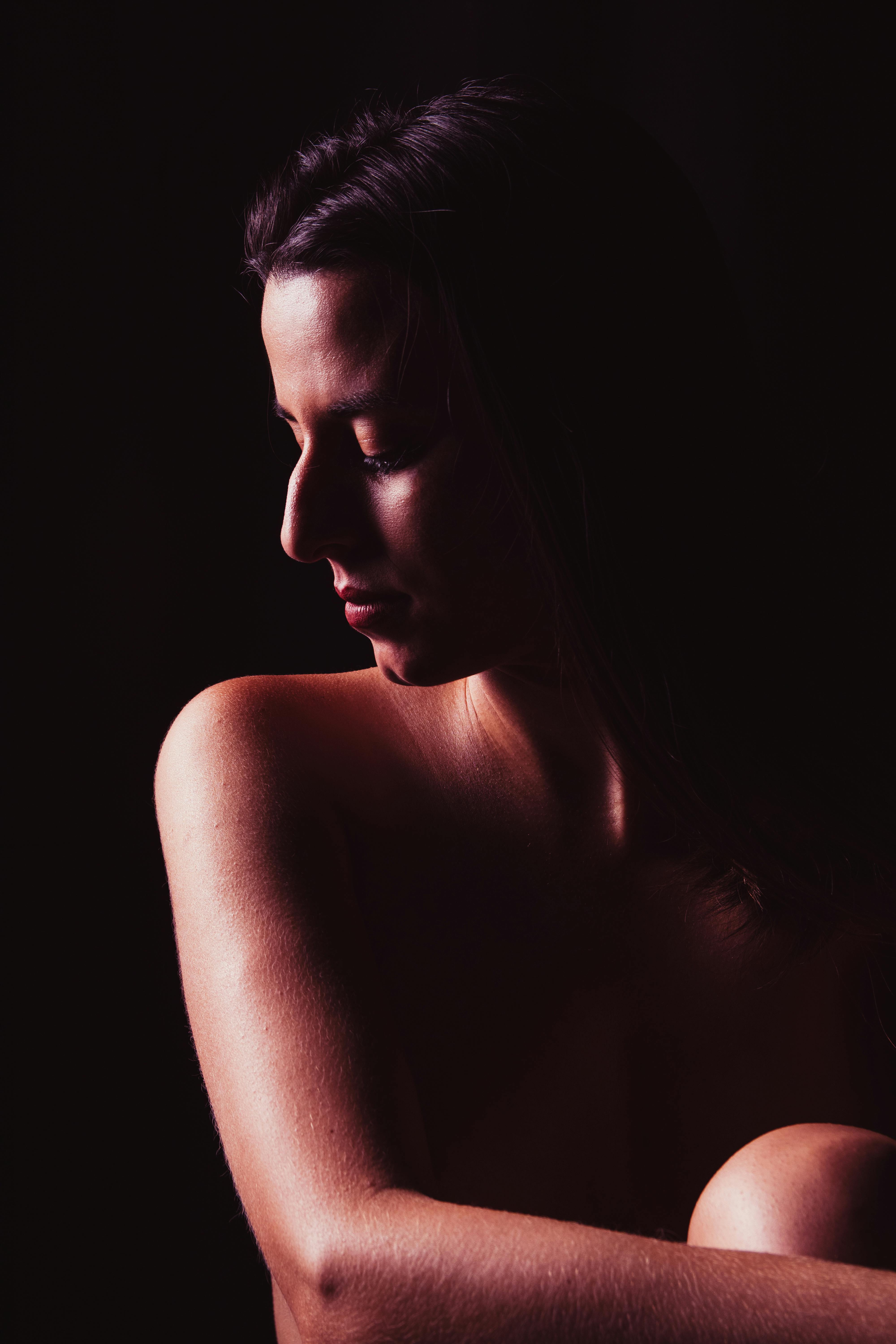 Sensual and thoughtful portrait of a woman in soft, moody lighting, embracing calmness.