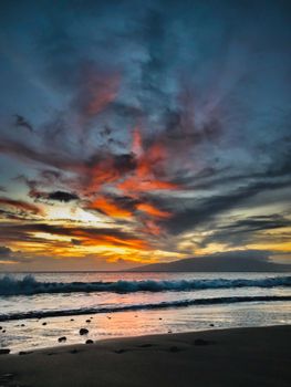 Breathtaking ocean sunset with dramatic clouds and crashing waves on the shore.