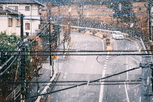 Car driving on railroad in residential district on snowy day