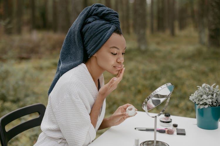 Woman With Towel On Hair Putting Facial Cream