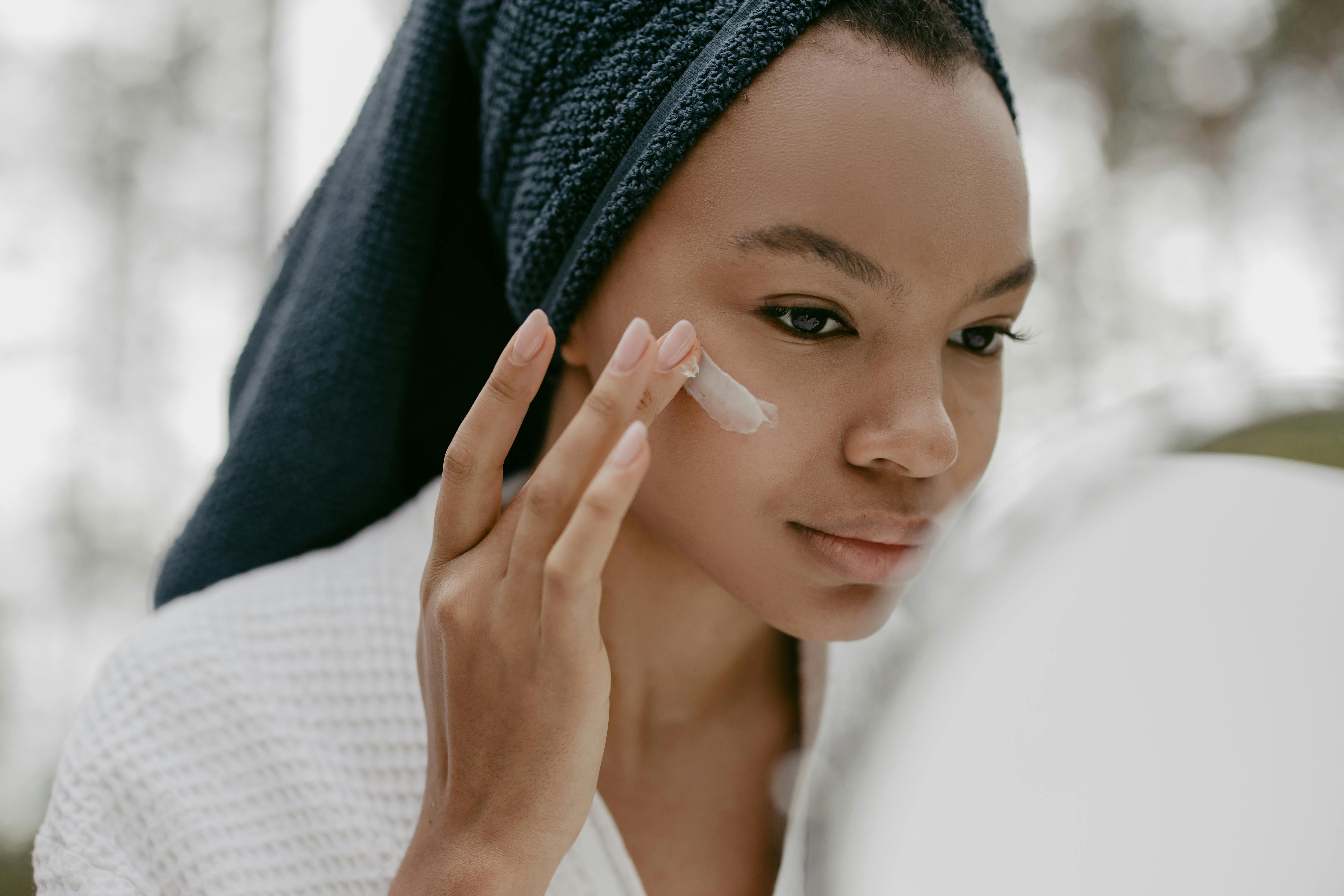 Free Woman Wearing Bathrobe Putting Facial Cream Stock Photo