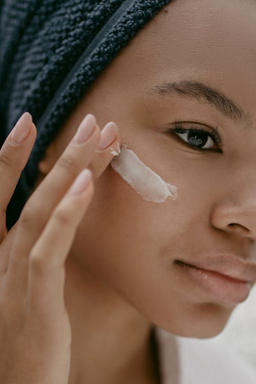 Free Woman Putting Face Cream on Cheek Stock Photo