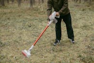 Man in Brown Jacket and Black Pants Holding Red and White Stick