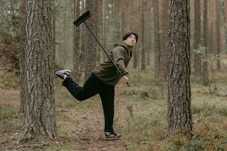 A Man Holding A Black Broomstick