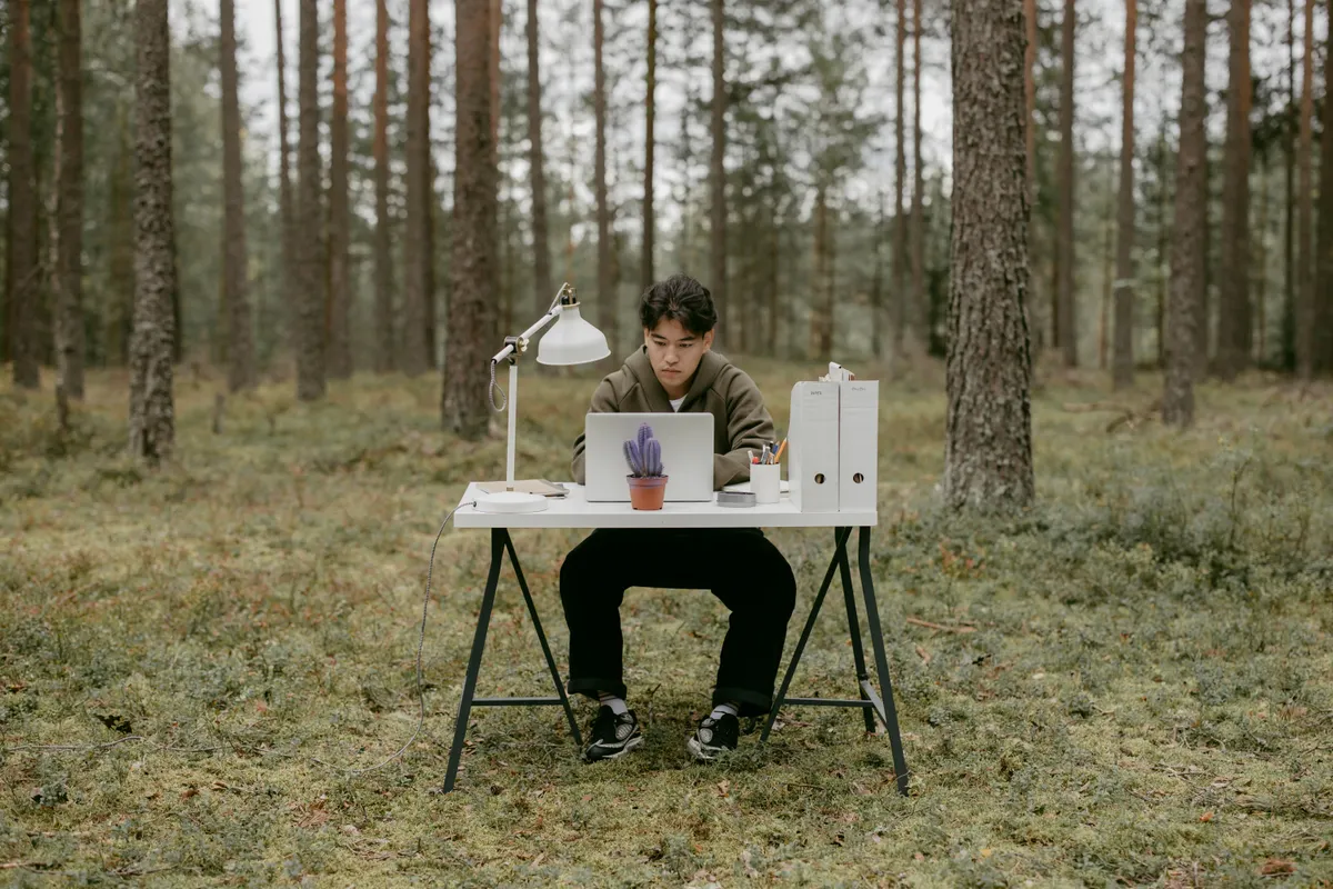A person working from a laptop at a small table, similar to a hands-off automated setup being monitored between travel stops.