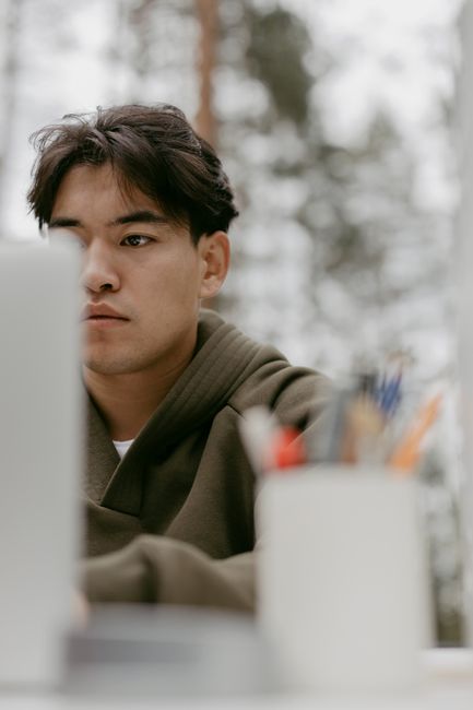 Young man intently working outdoors, wearing a green jacket, with a blurred background. Young man intently working outdoors, wearing a green jacket, with a blurred background.