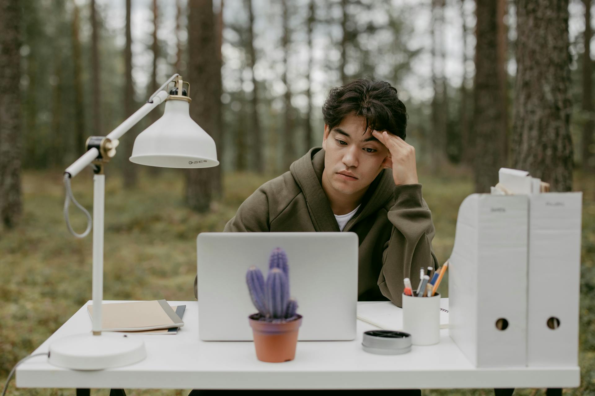 Man working remotely on laptop in forest, capturing the digital nomad lifestyle.