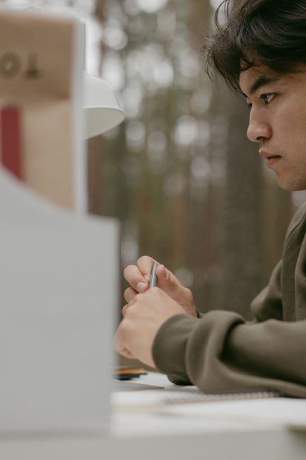 Young man writing in a notebook outdoors, deep in thought, surrounded by nature. Young man writing in a notebook outdoors, deep in thought, surrounded by nature.