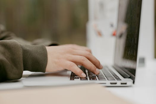 Close-up of hands typing on a laptop keyboard, ideal for technology and lifestyle themes.