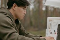 A Man in Jacket Seriously Looking at the Screen of the Monitor