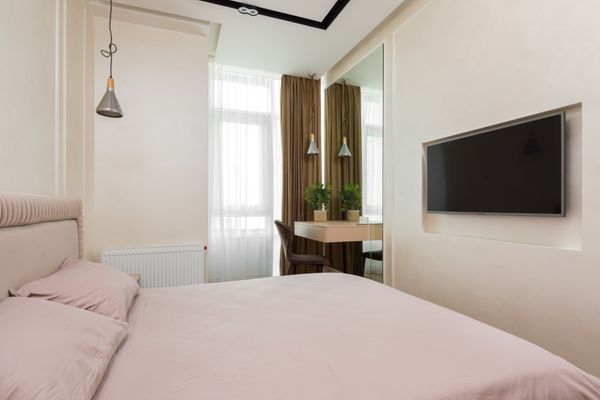 Compact bedroom with a large mirror beside a small window, making the most of a tight space