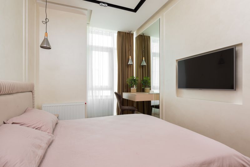 Compact bedroom with a large mirror beside a small window, making the most of a tight space