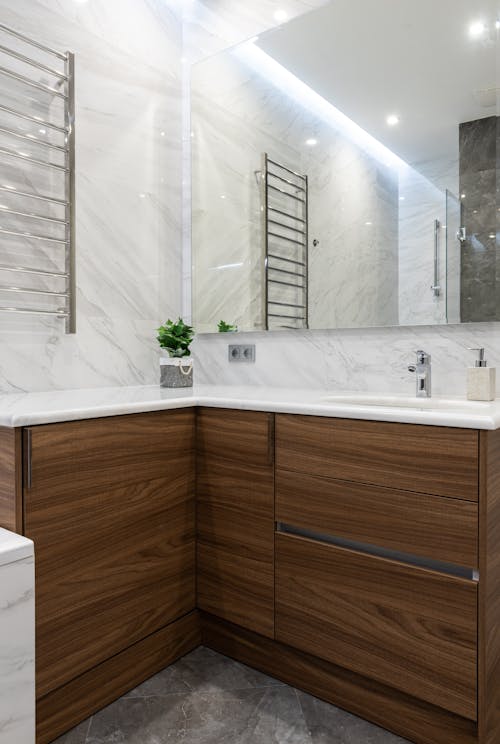 Interior of modern light bathroom with sink and tap on cabinets under mirror