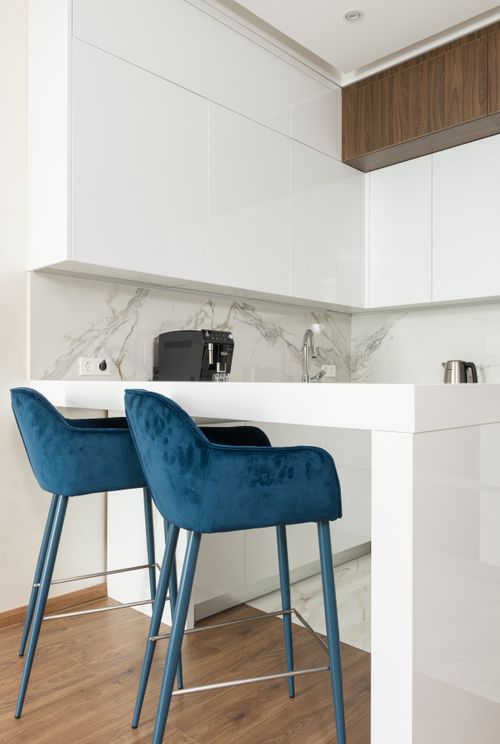 Free Comfortable blue chairs placed near white bar table in light kitchen with white cupboards in modern apartment Stock Photo
