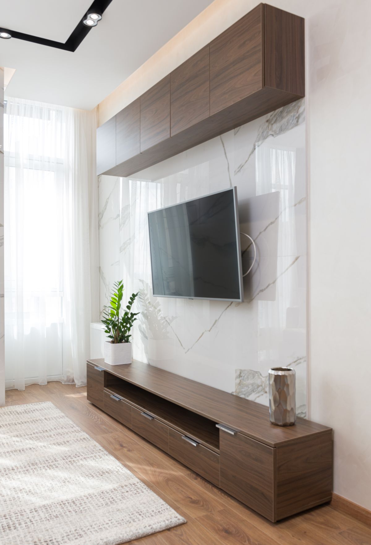 Sala de estar clara com TV na parede, painel baixo e visual organizado