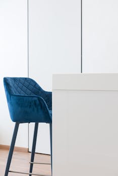 A stylish and contemporary interior design featuring a blue velvet chair and minimalist decor.