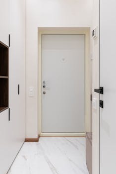 White wardrobe with wooden shelves and soft pouf in corridor of modern apartment
