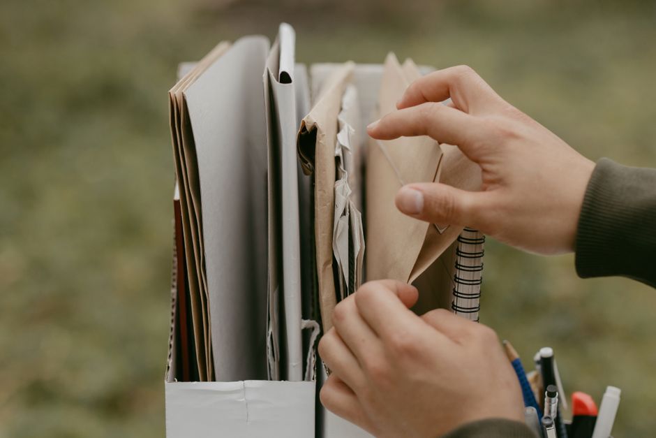 Hands organizing documents and envelopes, emphasizing office work and organization outdoors. Hands organizing documents and envelopes, emphasizing office work and organization outdoors.