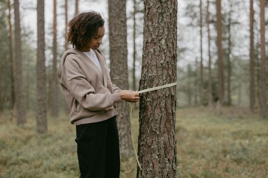 Woman in Gray Hoodie Measuring A Tree Trunk