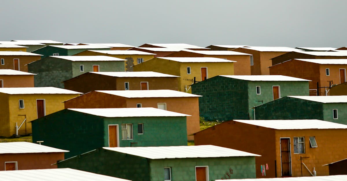 A vibrant cluster of colorful rectangular houses with white roofs in an urban setting under a cloudy sky.