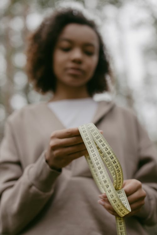 Woman in Gray Hoodie Holding A Tape Measure