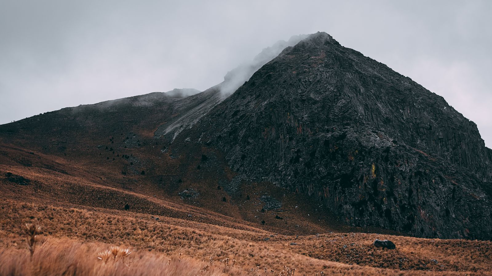 Brown grass field near a volcano under cloudy sky, Rwanda