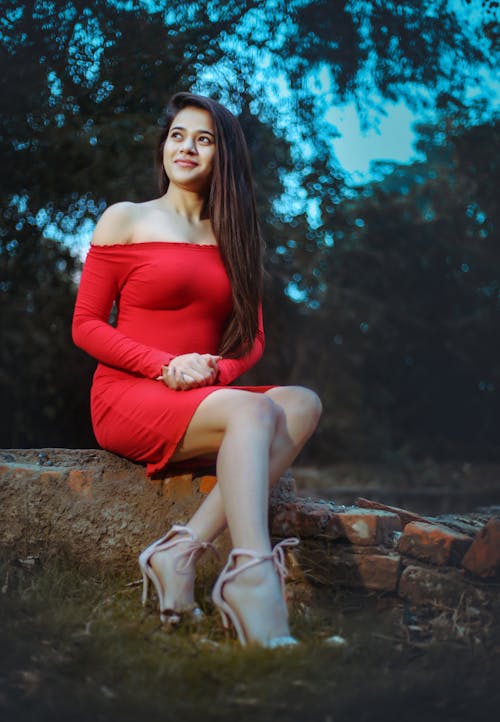 Free Woman in Red Off Shoulder Long Sleeve Dress Sitting on Red Bricks Stock Photo