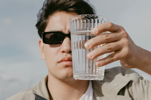 Man Covering Half of His Face With A Glass Of Water 