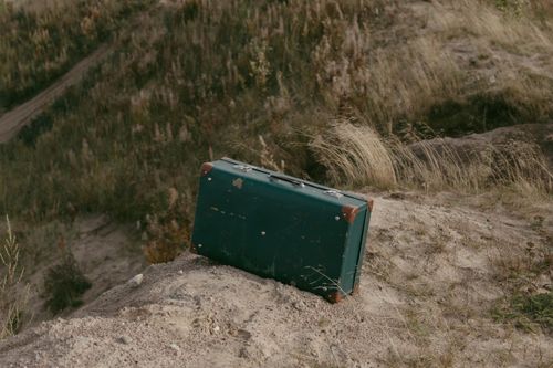 Free An old suitcase resting on a natural grassy hilltop, symbolizing adventure. Stock Photo