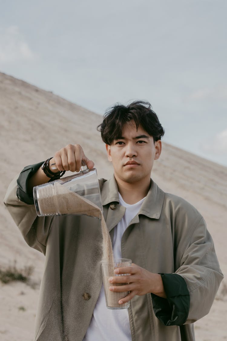 Man Pouring Sand From A Pitcher To A Drinking Glass