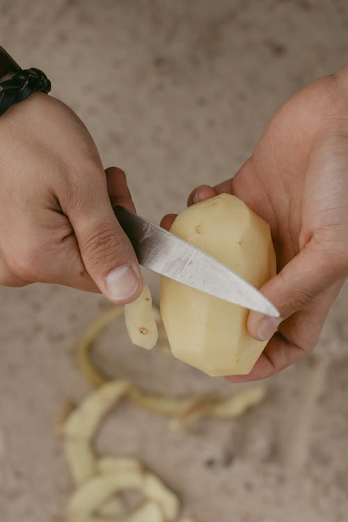 Free Person Peeling A Potato With A Knife Stock Photo