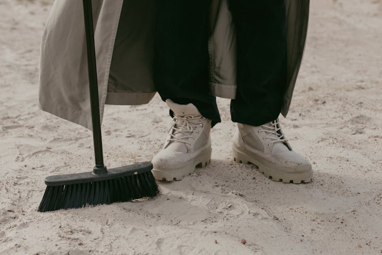 A Black Broom Near A Person's Feet