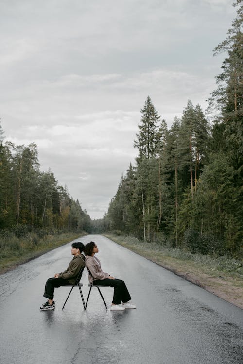 A Man and Woman Sitting Back to Back in the Middle of the Road