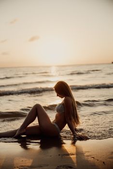 A serene scene of a woman sitting on a beach facing the sunset, capturing a tranquil moment.