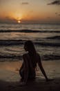 巴厘岛令人惊叹的日落期间，一名女子坐在沙滩上的剪影