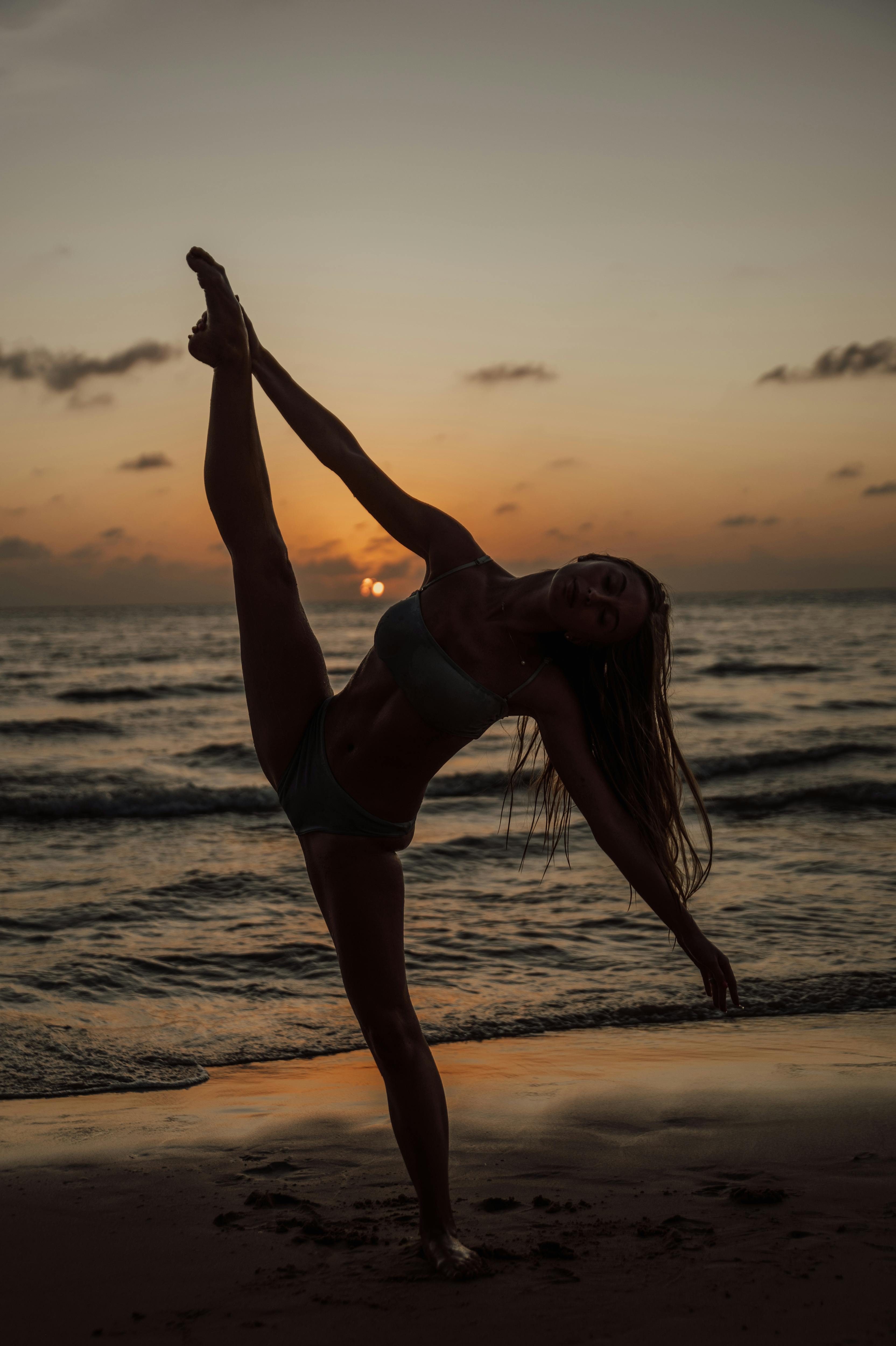 silhouette of a woman practicing yoga on the Bali beach in the