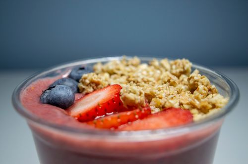 Free Healthy acai bowl topped with fresh strawberries, blueberries, and granola in a close-up view. Stock Photo