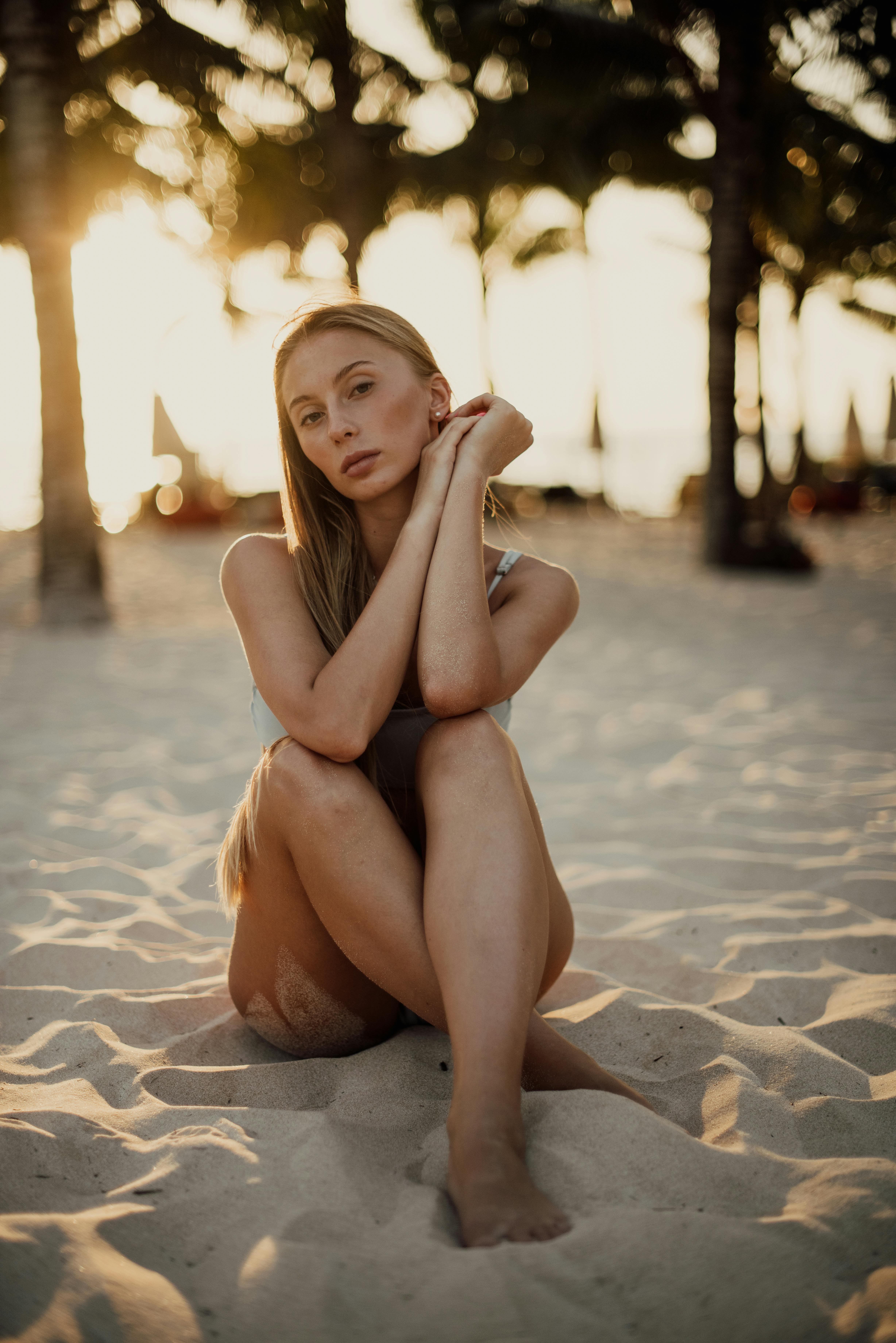 日落时分，一名穿着泳衣的女子坐在巴厘岛的沙滩上，享受着宁静的时刻