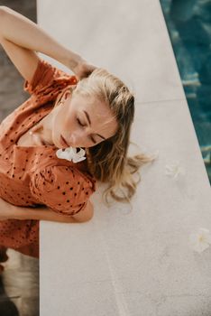 Woman in a polka dot dress relaxing by the poolside in Bali, Indonesia.